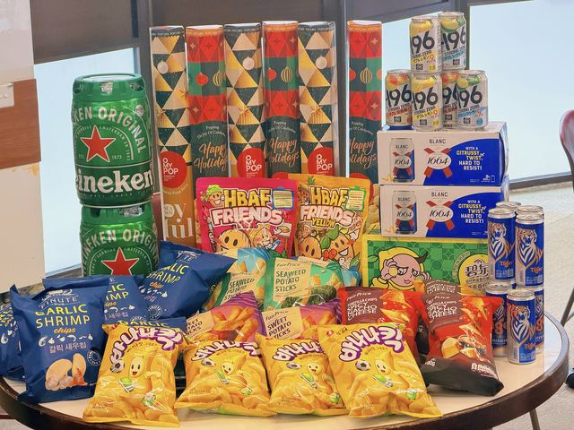 Event supplies on a table: beer kegs, canned drinks, popcorn and snack packs
